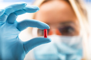 female scientist holding a red transparent pill